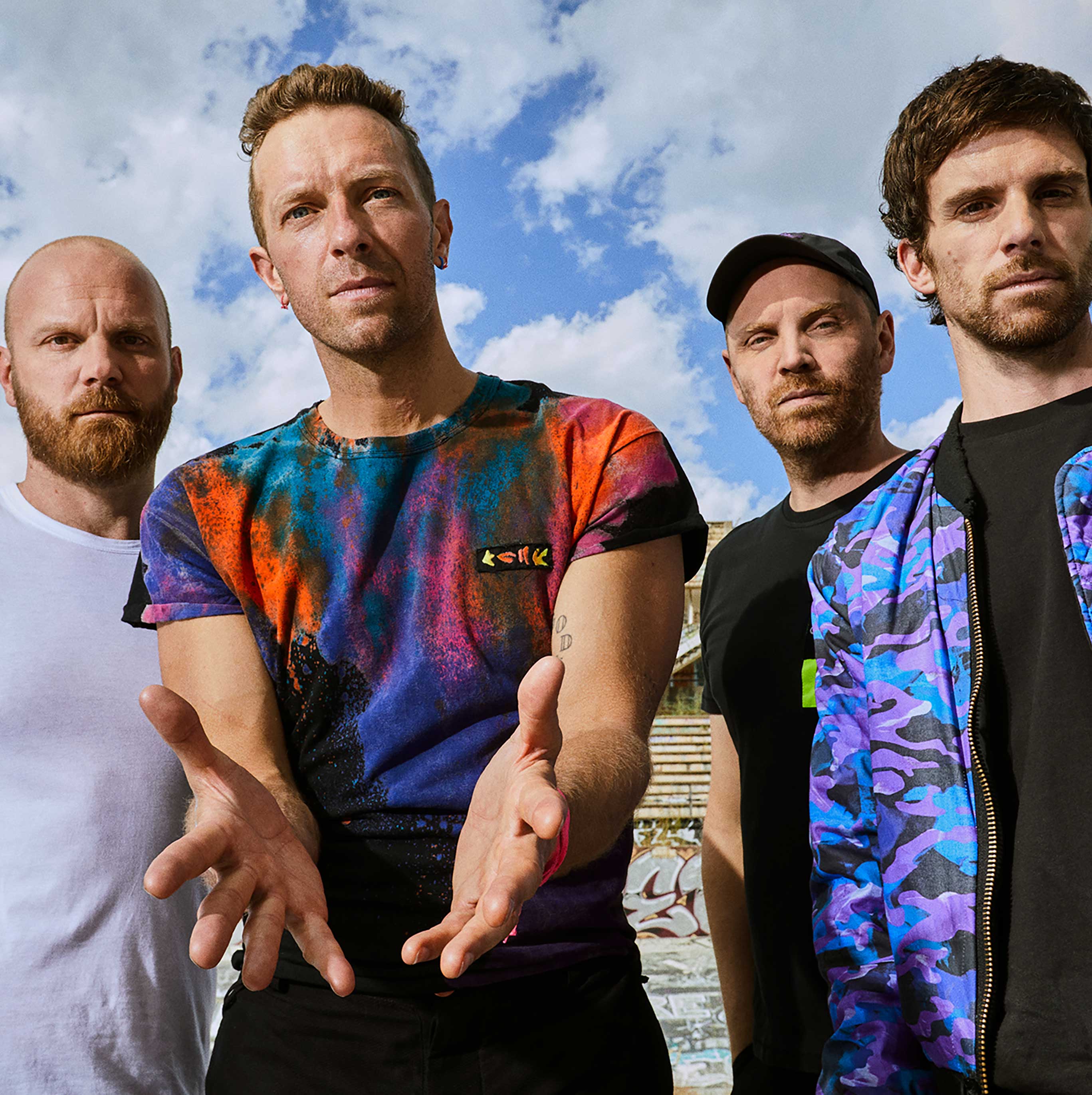 Coldplay posing in front of a blue sky