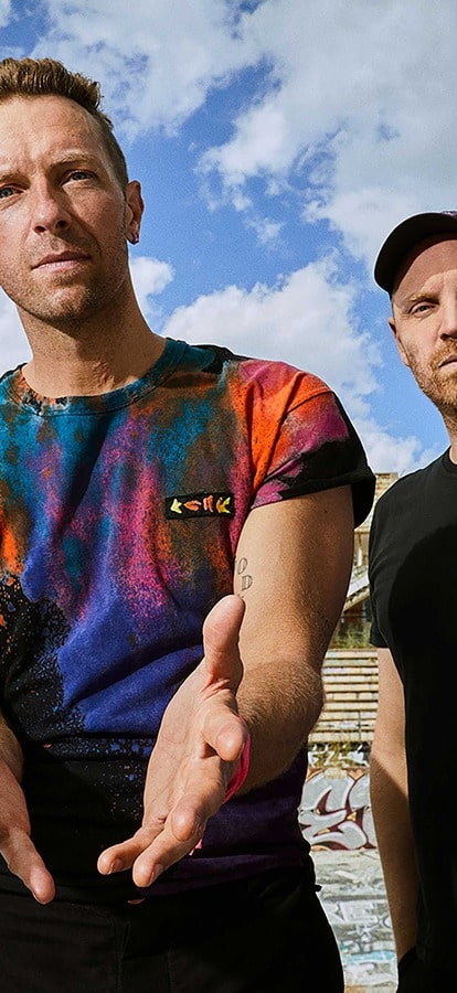 Coldplay posing in front of a blue sky